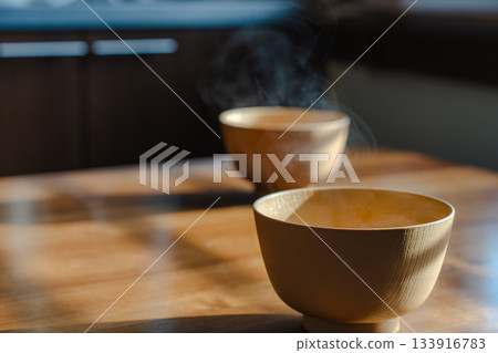 Breakfast scene with steaming miso soup and a wooden table in the morning light 133916783