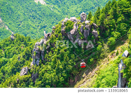 A red gondola passing in front of the Fujimiiwa Observatory on the Gozaisho Ropeway (Komono Town, Mie Prefecture) 133918065