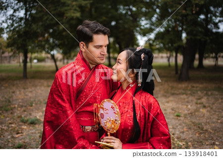 Multicultural bridal couple celebrating traditional Chinese wedding outdoors 133918401