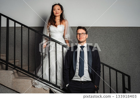 Interracial wedding couple posing on a staircase Interracial wedding couple posing on a staircase 133918403