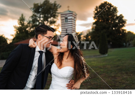 Happy newlywed multi-ethnic couple celebrating wedding outdoors at sunset 133918416