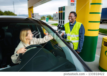 Woman paying for fuel with contactless terminal at gas station 133918422