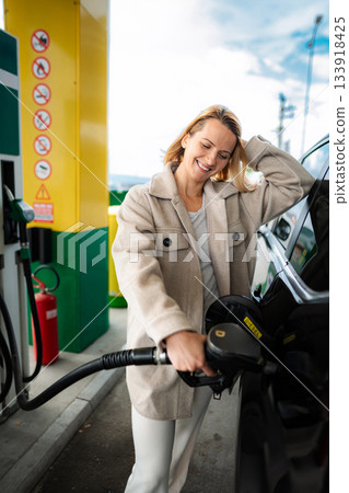 Smiling woman refueling car with diesel at gas station Smiling woman refueling car with diesel at gas station 133918425