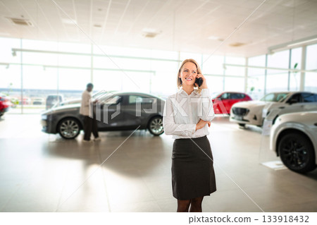 Businesswoman talking on phone at car dealership showroom 133918432