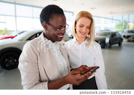Car salesperson showing customer information on mobile phone 133918458