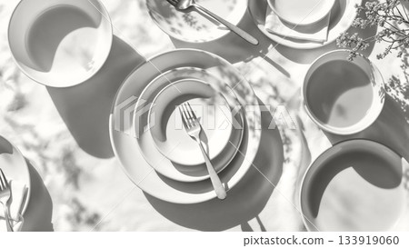 Setting a minimalist white dining table with empty plates, bowls, and cutlery under dappled sunlight. Modern trendy tone hue shade cloud dancer color of the year 2026 133919060