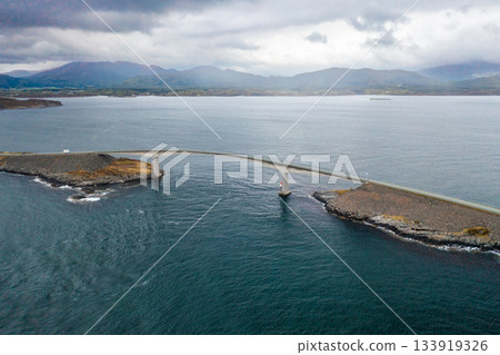 Iconic arch of the Atlantic Ocean Road showcasing the elegant curve of Storseisundet Bridge against Norways rugged coastal scenery. Iconic arch of the Atlantic Ocean Road showcasing the elegant curve of Storseisundet Bridge against Norways rugged coastal scenery. 133919326