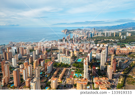 Aerial view of Benidorm skyline filled with high rise towers along the coast. Bright sunny weather and clear sea make this Spanish city a favorite tourist destination. 133919333