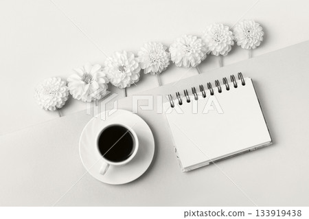 Demonstrating the colors of 2026 - Cloud Dancer. Opened blank notepad with flowers and a cup of coffee. Festive office desktop concept. 133919438