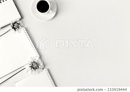Demonstrating the colors of 2026 - Cloud Dancer. Opened blank notepad with flowers and a cup of coffee. Festive office desktop concept. Demonstrating the colors of 2026 - Cloud Dancer. Opened blank notepad with flowers and a cup of coffee. Festive office desktop concept. 133919444