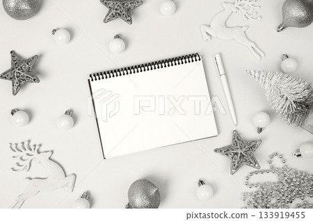 Demonstrating the colors of 2026 - Cloud Dancer. Christmas composition of stars and toys on Christmas tree, with open blank notebook and pen for writing goals and plans for the New Year. Demonstrating the colors of 2026 - Cloud Dancer. Christmas composition of stars and toys on Christmas tree, with open blank notebook and pen for writing goals and plans for the New Year. 133919455