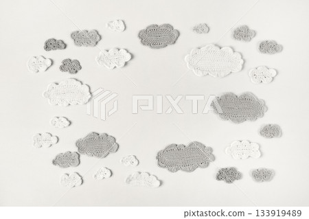 Demonstrating the colors of 2026 - Cloud Dancer. Knitted toys white and gray clouds. Baby stuff and accessories. Top view, flat lay, banner 133919489