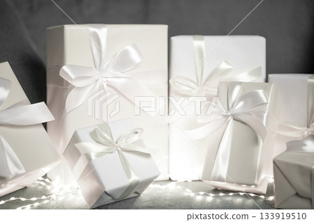 White gift boxes with silk ribbons and festive lights. Color of 2026 year dancer in the white cloud 133919510
