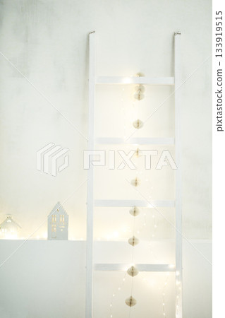 Minimalist christmas home decor with festive lights ladder. Color of 2026 year dancer in the white cloud Minimalist christmas home decor with festive lights ladder. Color of 2026 year dancer in the white cloud 133919515