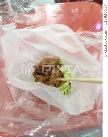 Spicy fried chicken street food plastic bag skewer cucumber red table casual dining night market vibe Spicy fried chicken street food plastic bag skewer cucumber red table casual dining night market vibe 133920517