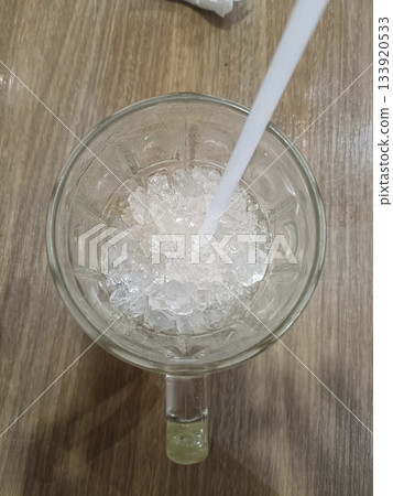 Iced drink glass mug crushed ice white straw top view wooden table refreshment cold beverage 133920533