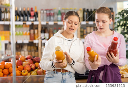 Young women choosing juices in grocery store 133921613