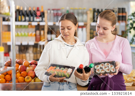 Young women choose sushi and sauces for them 133921614