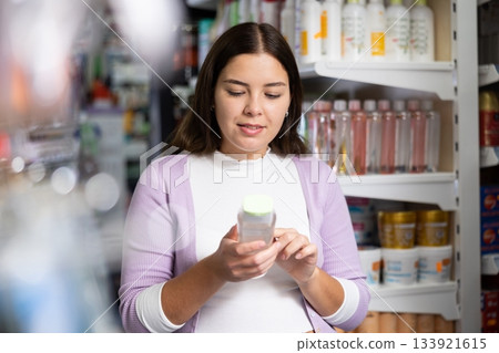 Young woman is choosing new conditioner in hair care store 133921615