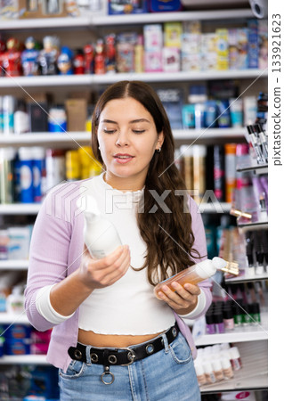 Focused girl shopping in cosmetics store looking for hair care treatments Focused girl shopping in cosmetics store looking for hair care treatments 133921623