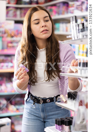 Girl buying lipstick or lip gloss in makeup store Girl buying lipstick or lip gloss in makeup store 133921634