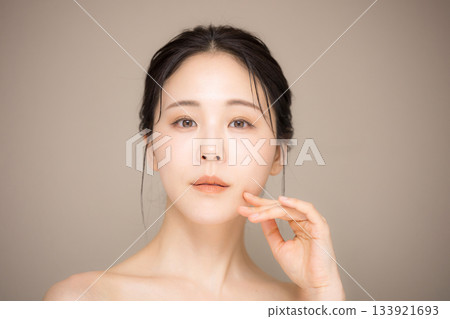 A close-up image of a beautiful woman with her hair up and a beige background, perfect for beauty and skincare. A close-up image of a beautiful woman with her hair up and a beige background, perfect for beauty and skincare. 133921693