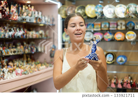 Happy young woman choosing statue of Spanish dancer among various souvenirs in gift shop in Barcelona Happy young woman choosing statue of Spanish dancer among various souvenirs in gift shop in Barcelona 133921711