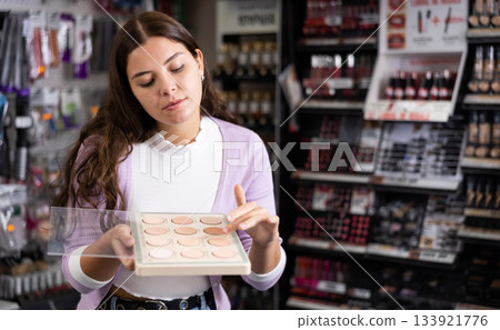 Female customer chooses face powder in cosmetic store Female customer chooses face powder in cosmetic store 133921776