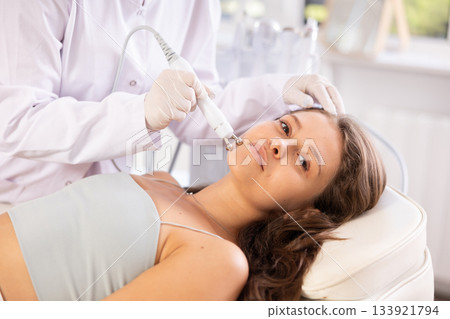 Young woman receiving facial radiofrequency procedure stimulating collagen production Young woman receiving facial radiofrequency procedure stimulating collagen production 133921794