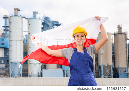 Happy woman waving flag of Poland against the background of modern factory 133921837