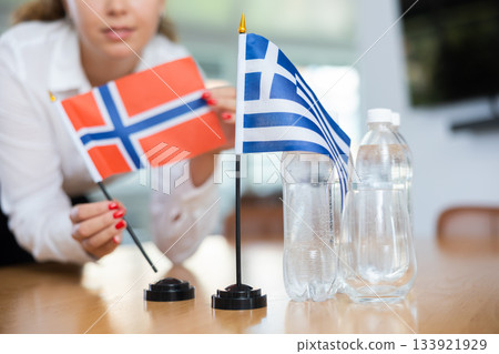 Young female secretary preparing room for international negotiations between greece and norway 133921929