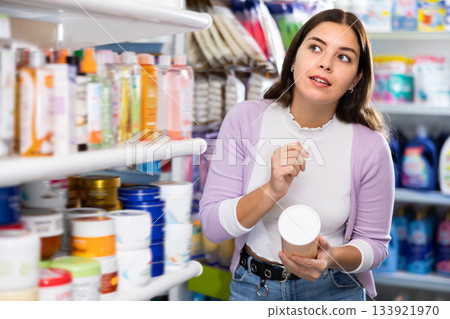Female purchaser searching for reliable shampoo or conditioner in cosmetics store Female purchaser searching for reliable shampoo or conditioner in cosmetics store 133921970