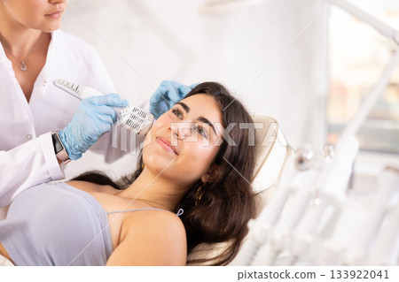 Brunette girl having facial beauty procedure with ice hummer 133922041