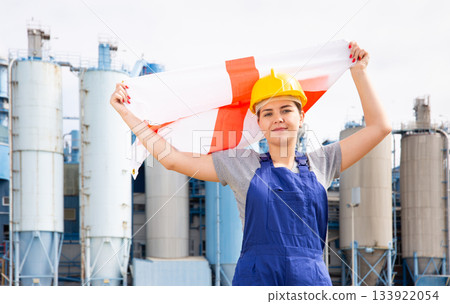 National flag of England in the hands of girl in overalls against background of modern metallurgical plant National flag of England in the hands of girl in overalls against background of modern metallurgical plant 133922054