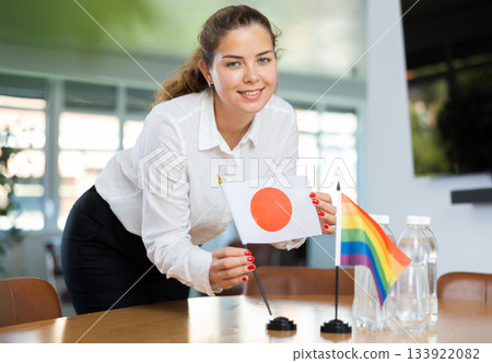 Young woman putting Japan and LGBT flags on table in office Young woman putting Japan and LGBT flags on table in office 133922082
