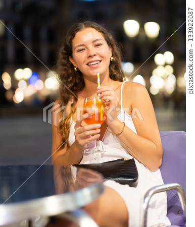 Young woman with a cocktail in her hands is sitting in the square Young woman with a cocktail in her hands is sitting in the square 133922087