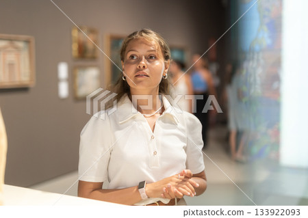 Girl walks around museum hall, view exhibition items 133922093