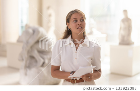 Woman with sheet piece of paper in hands view sculpture in museum hall 133922095