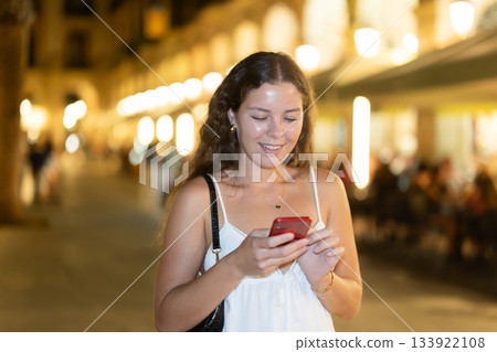 Young woman with phone in hands near restaurants Young woman with phone in hands near restaurants 133922108