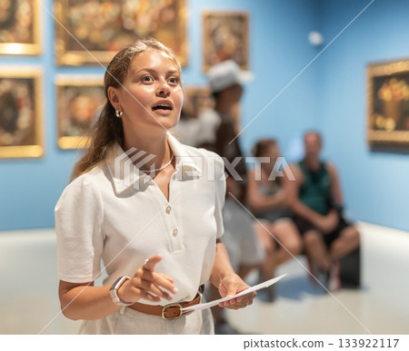 Woman with sheet piece of paper in hands view pictures and icons in museum hall 133922117