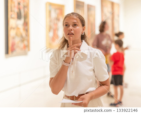 Portrait of young girl visitor with paper guide at the exhibition of paintings in museum 133922146