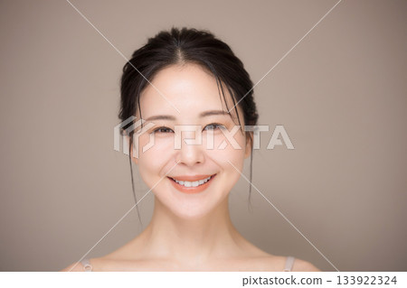 一位美麗女性的照片,頭髮盤起,背景是米色,易於用於美容和護膚,直視鏡頭。 一位美麗女性的照片,頭髮盤起,背景是米色,易於用於美容和護膚,直視鏡頭。 133922324