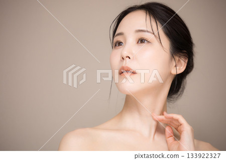 Image of a beautiful woman with her hair up and a beige background, easy to use for beauty and skin care, looking up Image of a beautiful woman with her hair up and a beige background, easy to use for beauty and skin care, looking up 133922327