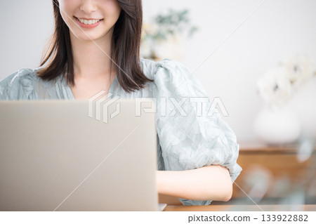 一位穿著休閒服、沒有臉的年輕可愛女子在家裡的房間裡使用筆記型電腦。 133922882