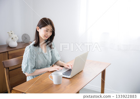 一位穿著休閒服的年輕時尚可愛女士在自家房間使用筆記型電腦 133922883