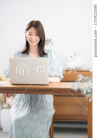 A young stylish and cute woman in casual clothes using a laptop in her home room A young stylish and cute woman in casual clothes using a laptop in her home room 133922890