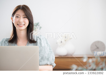 A young stylish and cute woman in casual clothes using a laptop in her home room 133922892