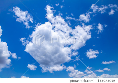 White Cumulus clouds floating across a bright blue sky 133923056