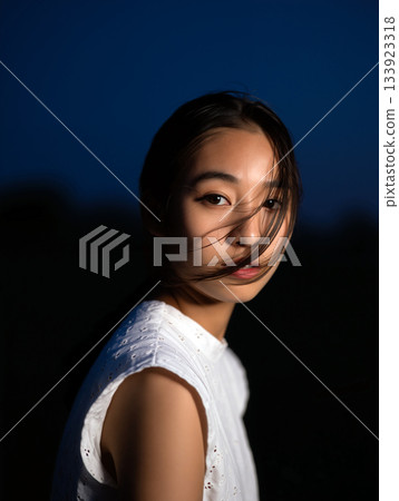 Young Woman Gazes Thoughtfully During Twilight With Soft Wind in Her Hair Young Woman Gazes Thoughtfully During Twilight With Soft Wind in Her Hair 133923318