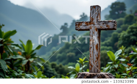 A cross against a backdrop of lush greenery, with mountains visible in the distance under an overcast sky. A cross against a backdrop of lush greenery, with mountains visible in the distance under an overcast sky. 133923399